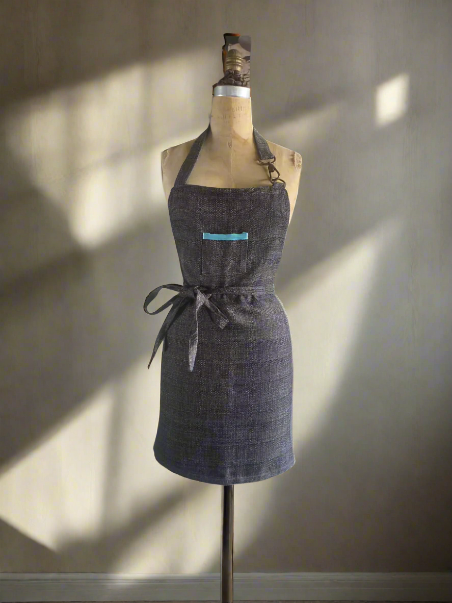 Lux apron on a mannequin with a neutral background and aqua trim pocket detail