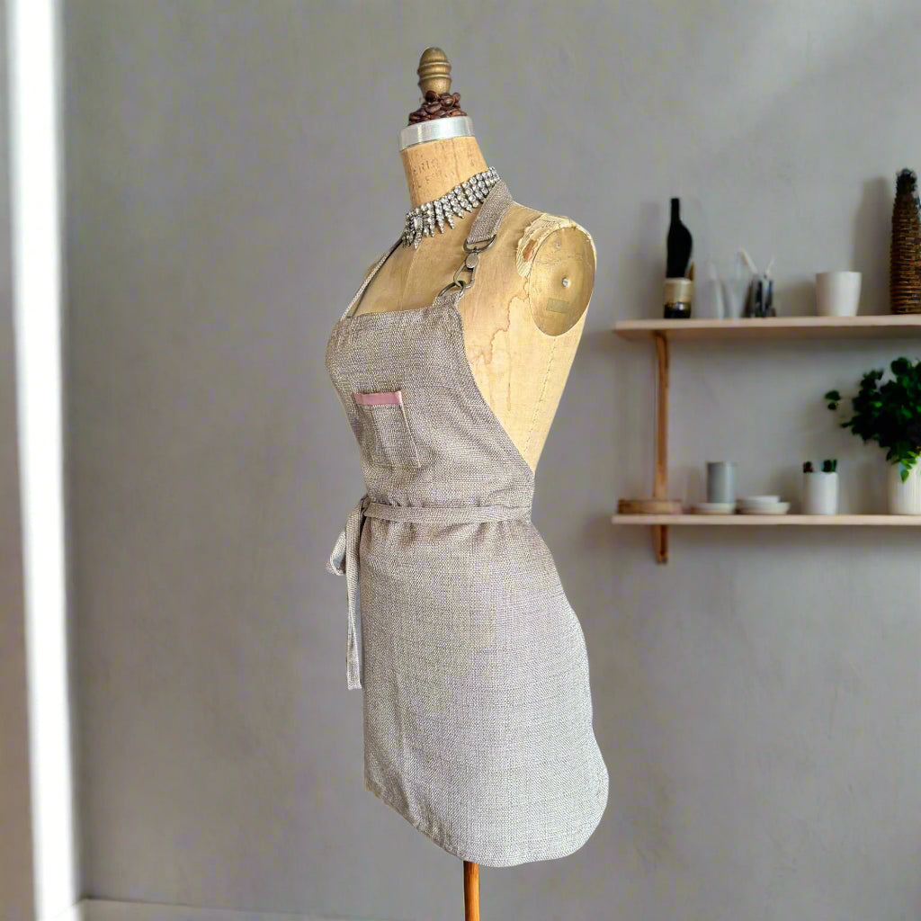 Light grey apron on a mannequin with pink satin pocket detail