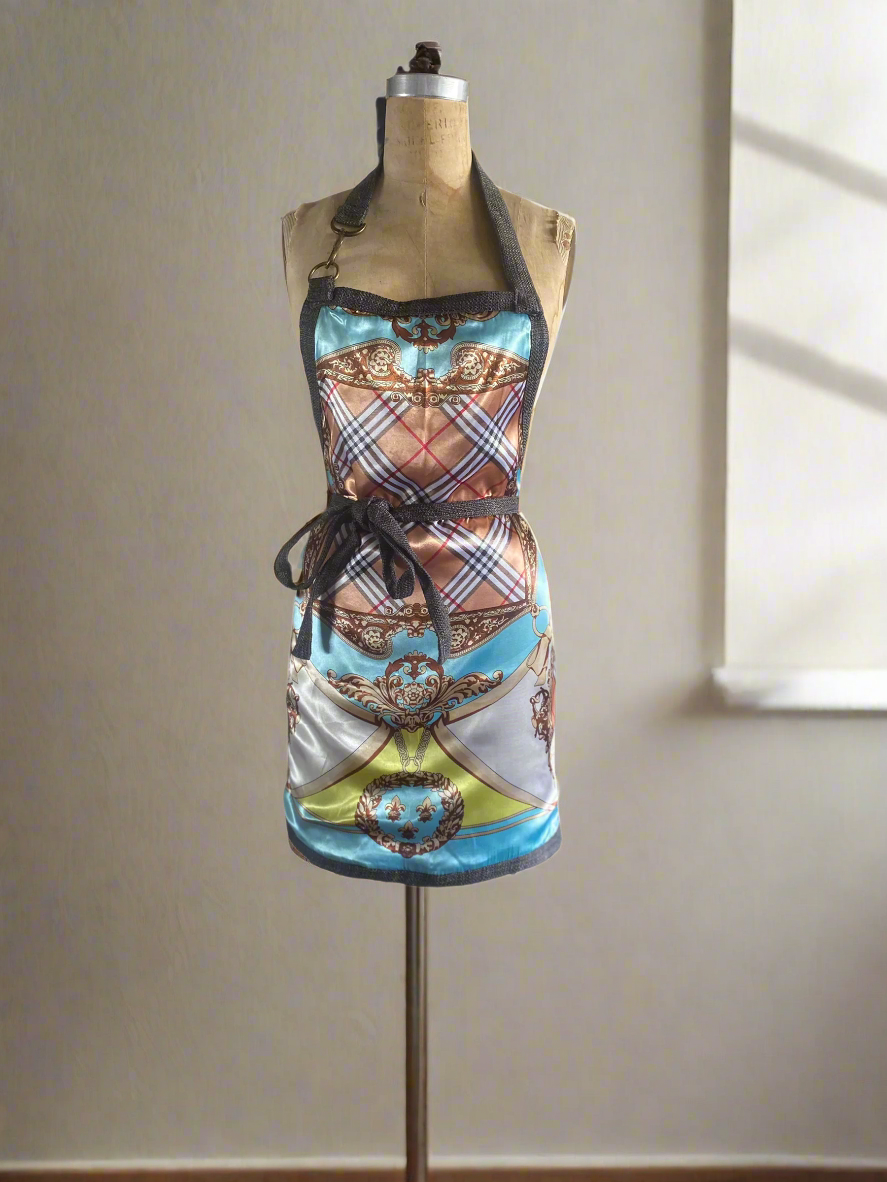 Apron showing the elegant pattern print side, featuring a double-sided, round edges design with a front pocket on the solid side, apron strap that ties around the waist, a snap hook detail on one side of the apron strap.