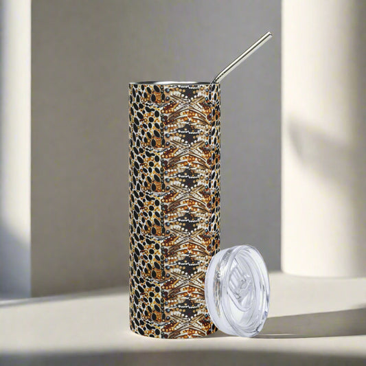 Skinny stainless steel tumbler in neutral snake pattern with metal straw and lid on gray backdrop