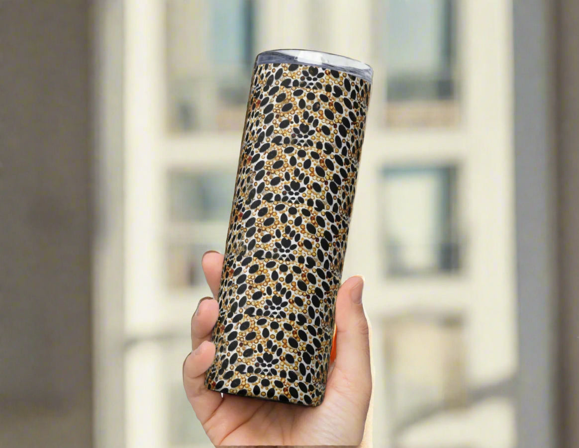 Hand holding sleek animal print tumbler with luxe black, gold, and beige snakeskin wrap