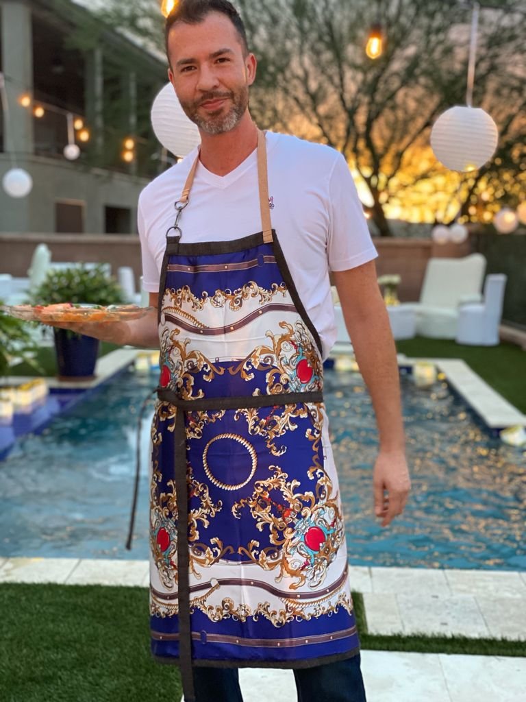 Front view of male home chef serving his guests and wearing luxury kitchen apron with leather strap and front pocket