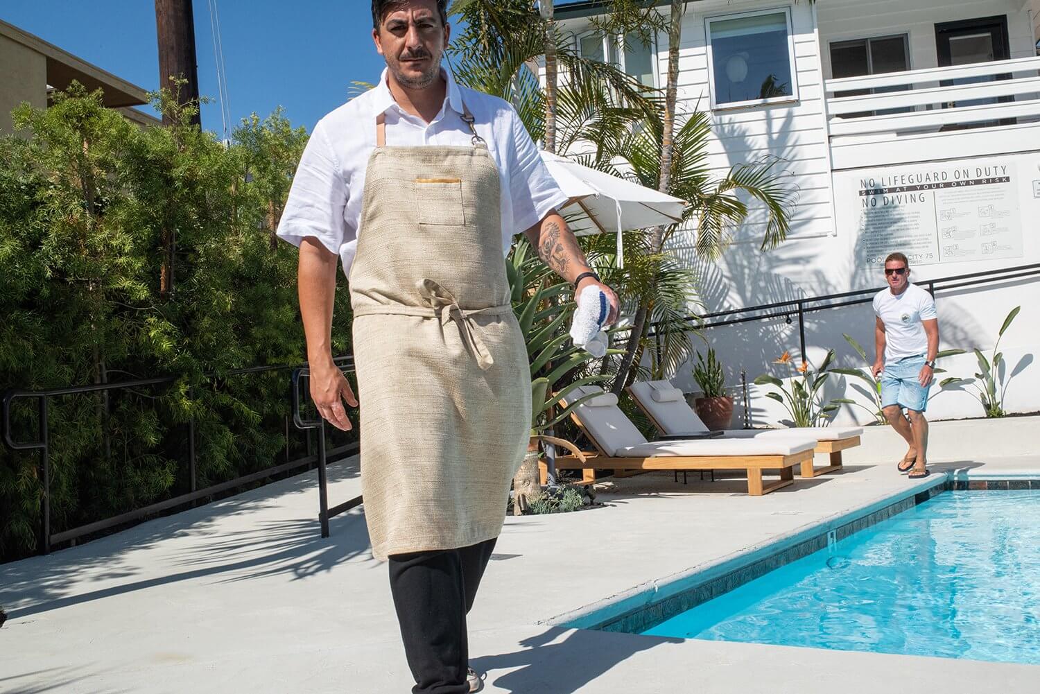 Man wearing natural linen apron by pool in elegant boutique hotel 