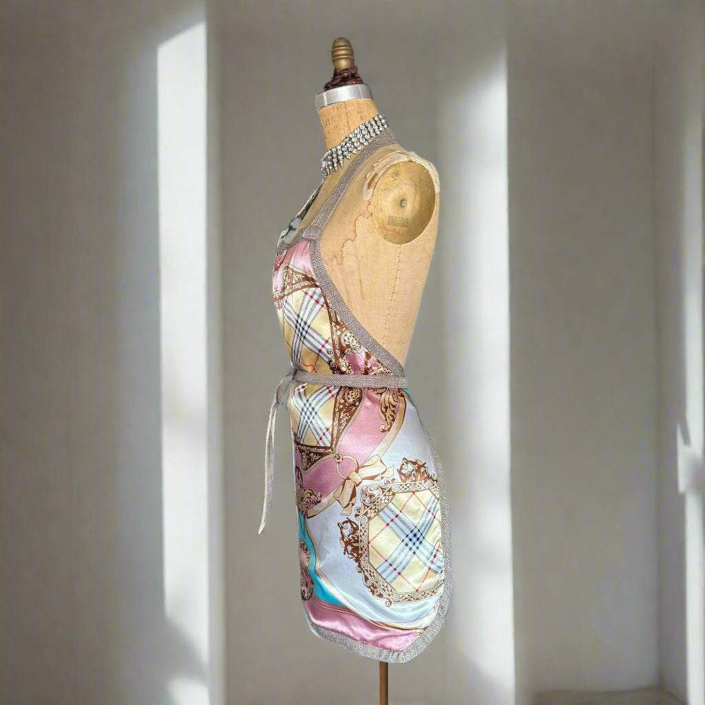 Mannequin wearing a blush pink luxury apron, against a beautifully lit grey room