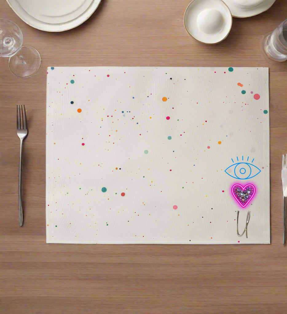 Cream placemat with colorful confetti paint dots and pink neon heart-eye graphic in corner